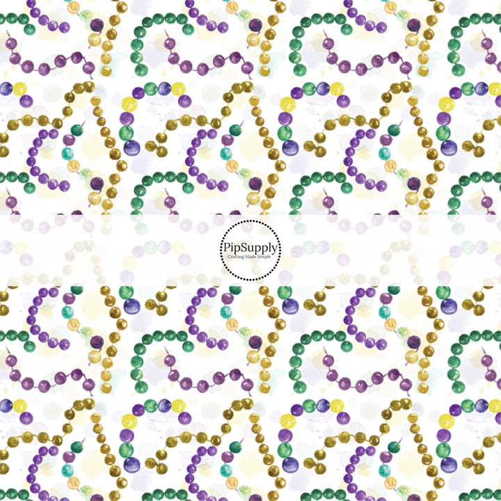 White fabric by the yard with yellow, purple, and green Mardi Gras beads.