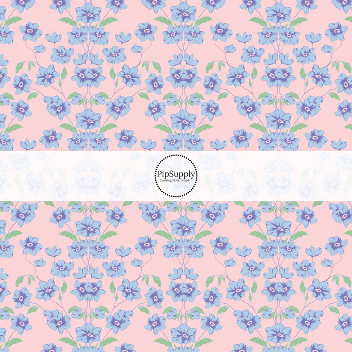 This spring floral themed fabric by the yard features blue flowers on pink. This fun pattern fabric can be used for all your sewing and crafting needs!