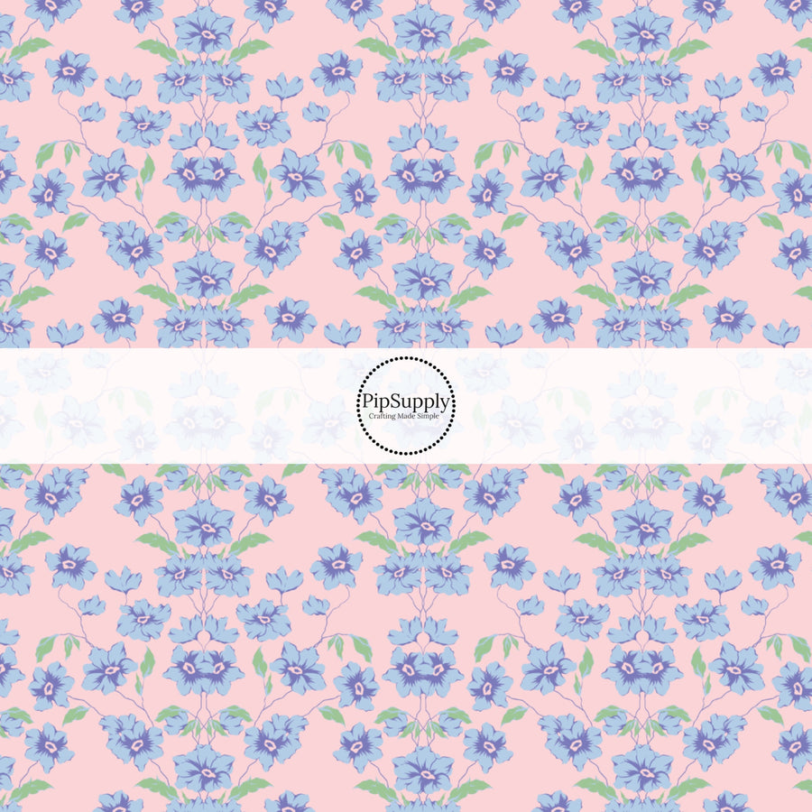 This spring floral themed fabric by the yard features blue flowers on pink. This fun pattern fabric can be used for all your sewing and crafting needs!