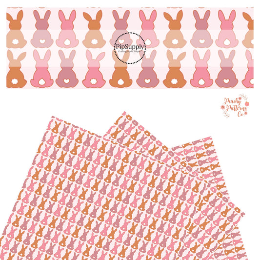 Pink, mauve, and brown bunnies sitting in a line with hearts, raindrop, and fluffy white tails on a pink faux leather sheet