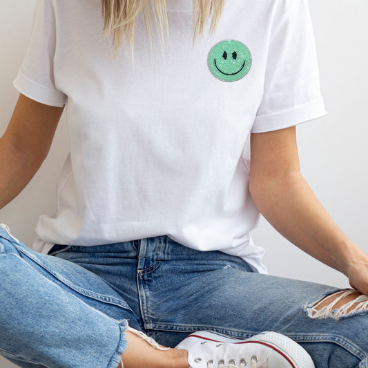 Aqua sequined smiley face iron on patch on a white t-shirt