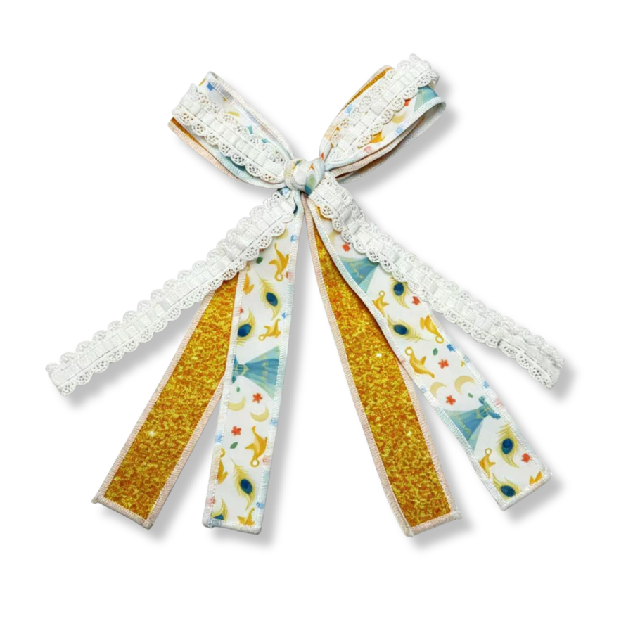 This three-ribbon tie bow features a charming fairytale-inspired design in soft gold, white, and pastel blue tones. One ribbon showcases a whimsical print with blue gowns, golden magic lamps, peacock feathers, crescent moons, stars, and delicate floral accents. A second ribbon adds sparkling golden glitter for extra shimmer and contrast. The third ribbon is a white lace trim with scalloped edges, bringing texture and an elegant finishing touch.
Bow Sizing 4" x 8"