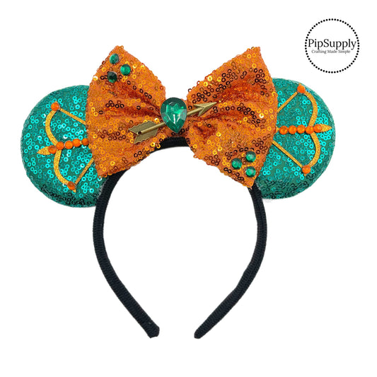 These teal mouse ear headbands are a stylish hair accessory. These comfortable headbands have an attached orange glitter bow and teal glitter mouse ears. Along with an arrow embellishment. This hair accessory comes completely assembled and is great for park vacations, costumes or for everyday wear.