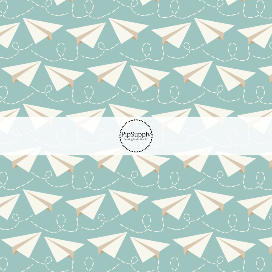 Light aqua fabric by the yard with white paper airplanes.