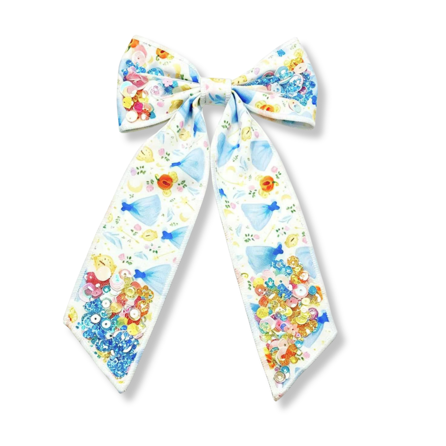This whimsical princess-inspired bow features a soft white ribbon printed with light blue ball gowns, golden pumpkin carriages, clocks, moons, florals, and delicate storybook details. The classic bow design is accented with colorful sequin embellishments clustered on each loop and at the ends of the tails, creating a sparkling, jewel-like effect. Shades of blue, gold, pink, and iridescent sequins add texture and shimmer while complementing the fairytale-themed print. 
Bow Sizing 5" x 8.5"
