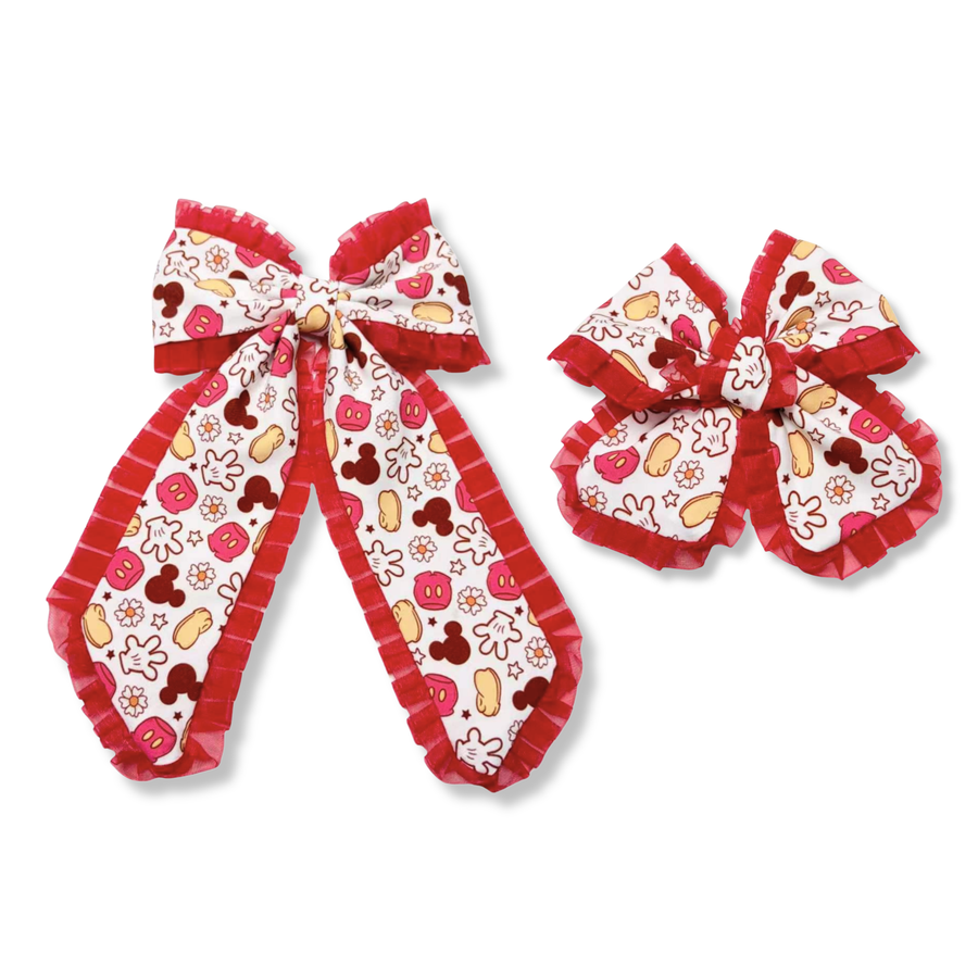 These charming bows feature a white ribbon printed with classic character-inspired icons, including gloves, shoes, mouse silhouettes, flowers, and stars in shades of red, yellow, black and white. Finished with vibrant red ruffle trim.  These bows add extra texture and dimension. Available in both a larger statement bow and a smaller matching style, they are perfect for themed outfits, park visits, or everyday wear.
choose size
Large 5.5" X 9.5"
Small 5" X 6"
