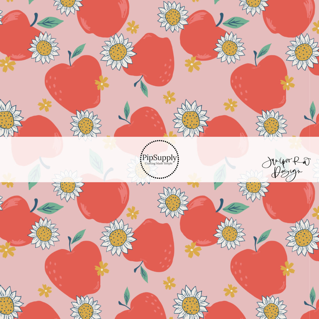 Red apples with white daisies on a light pink fabric with tiny yellow flowers scattered around