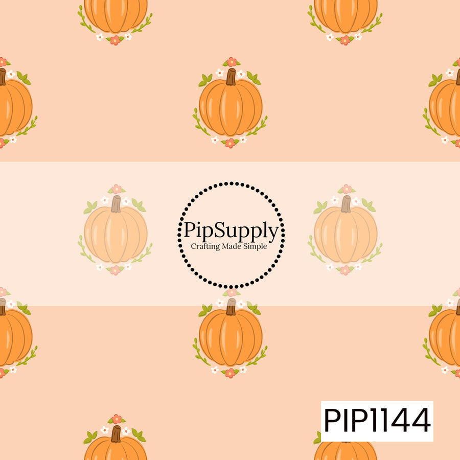A sweet autumn pattern featuring orange pumpkins framed by tiny coral and white flowers with green leafy sprigs, evenly scattered across a soft peach background.
