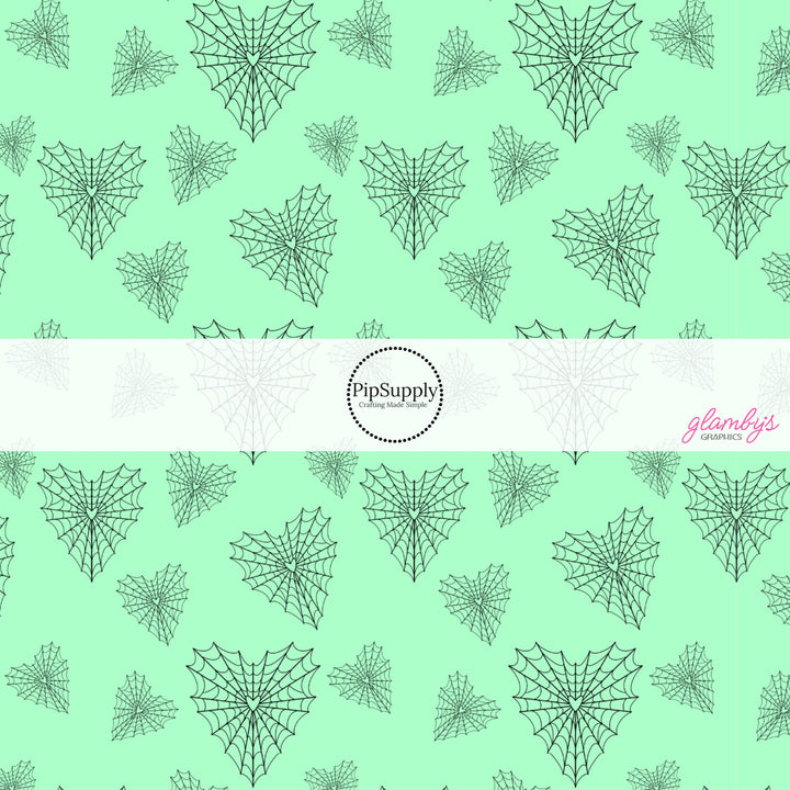 Mint green fabric by the yard with heart shaped spiderwebs.