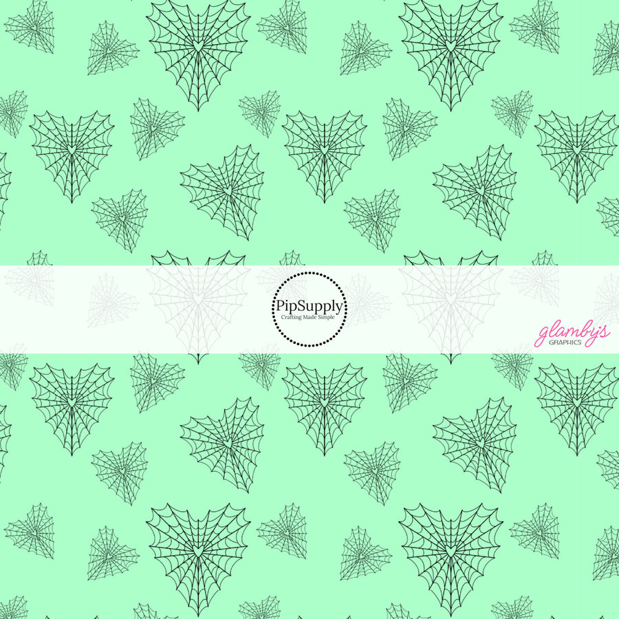 Mint green fabric by the yard with heart shaped spiderwebs.