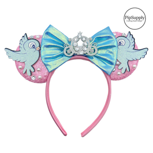 These pink and blue mouse ear headbands are a stylish hair accessory. These comfortable headbands have an attached blue bow and pink glitter mouse ears. Along with an pearls, rhinestone, and bird embellishment. This hair accessory comes completely assembled and is great for park vacations, costumes or for everyday wear!