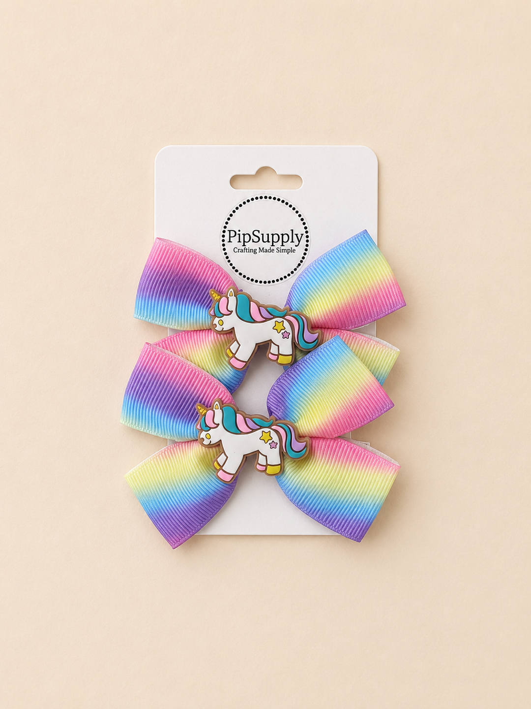 Two rainbow-colored hair bows with unicorn centers on hair clips. Sized approximately 3.25"