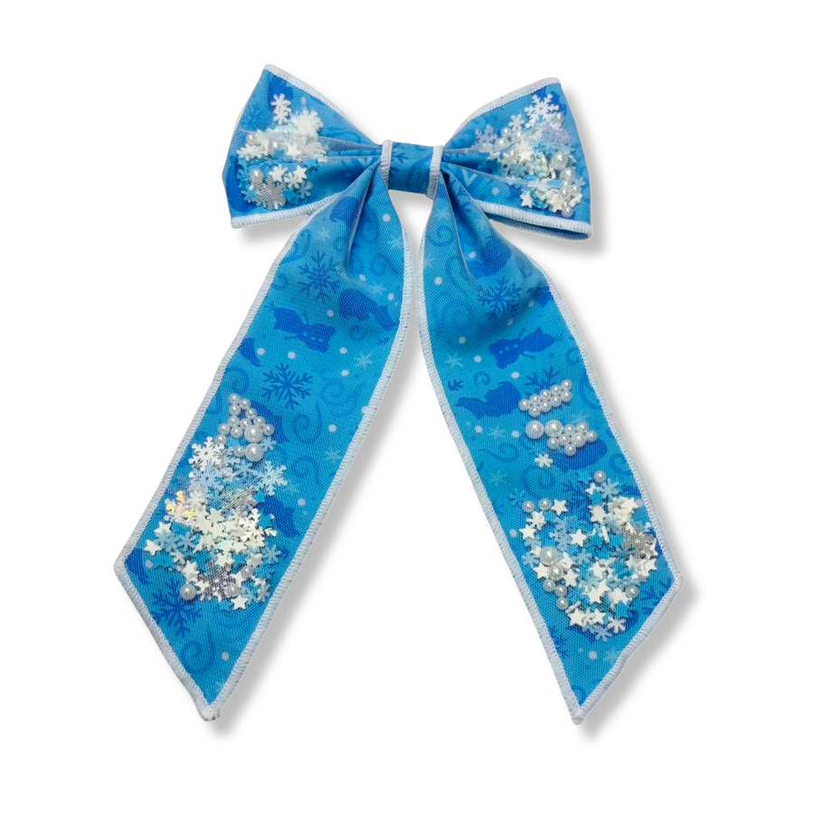 A magical winter-inspired long-tail shaker bow featuring icy blue fabric with delicate snowflake details and whimsical silhouette accents. The shaker pockets are filled with sparkling snowflakes, pearl embellishments, and iridescent confetti that add beautiful movement and frosty shimmer. The elegant long tails and snowy accents create an enchanting accessory perfect for capturing the magic of winter.

Bow Sizing 5" x 8.5"