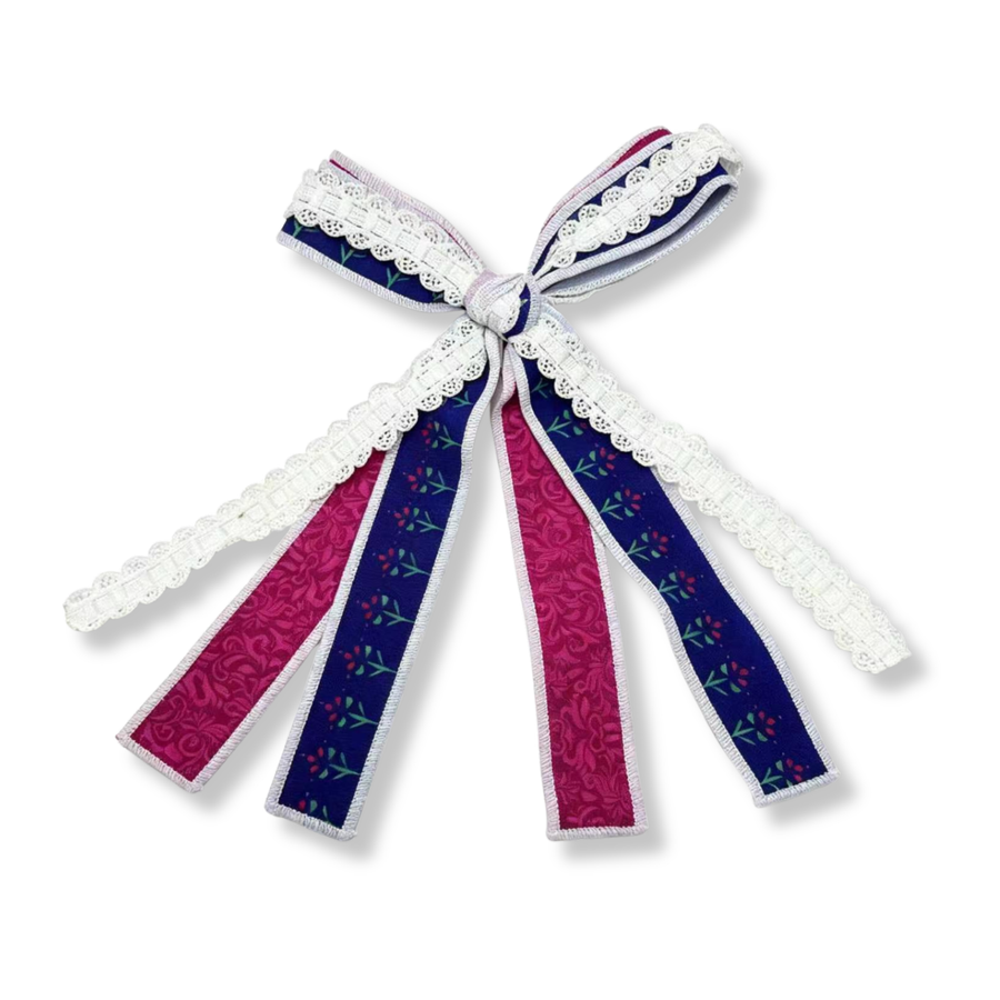 A charming layered ribbon bow featuring rich royal purple and vibrant berry pink ribbons accented with delicate white lace trim. The long flowing tails and elegant lace details create a sweet, vintage-inspired look with a touch of storybook charm and timeless sophistication.
Bow Sizing 4" x 8"