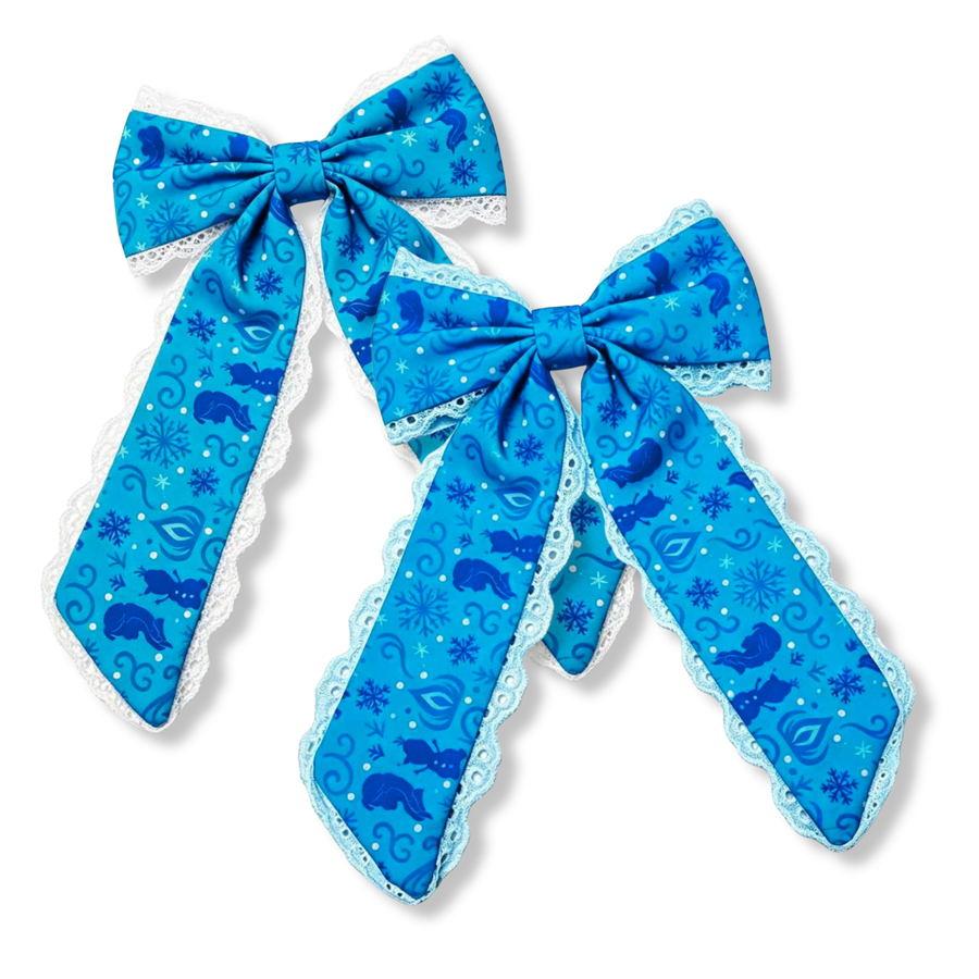 These charming long-tail bows feature a vibrant blue winter-inspired print adorned with snowflakes, swirling accents, and whimsical silhouette details. Delicate white or blue lace trim frames the edges, adding a soft, elegant touch that complements the frosty design. The flowing tails and graceful silhouette create a magical accessory perfect for winter celebrations and seasonal styles. 
You choose lace color
Large 5.5" X 9.5"
