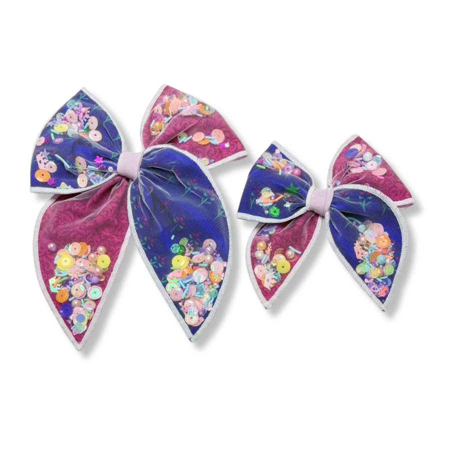 Whimsical shaker bows featuring contrasting pink and purple panels covered with a sheer overlay and filled with colorful sequins, stars, and sparkling embellishments. 
Small 4.5" x 4.5"
Large 6.5" x 6.5"

