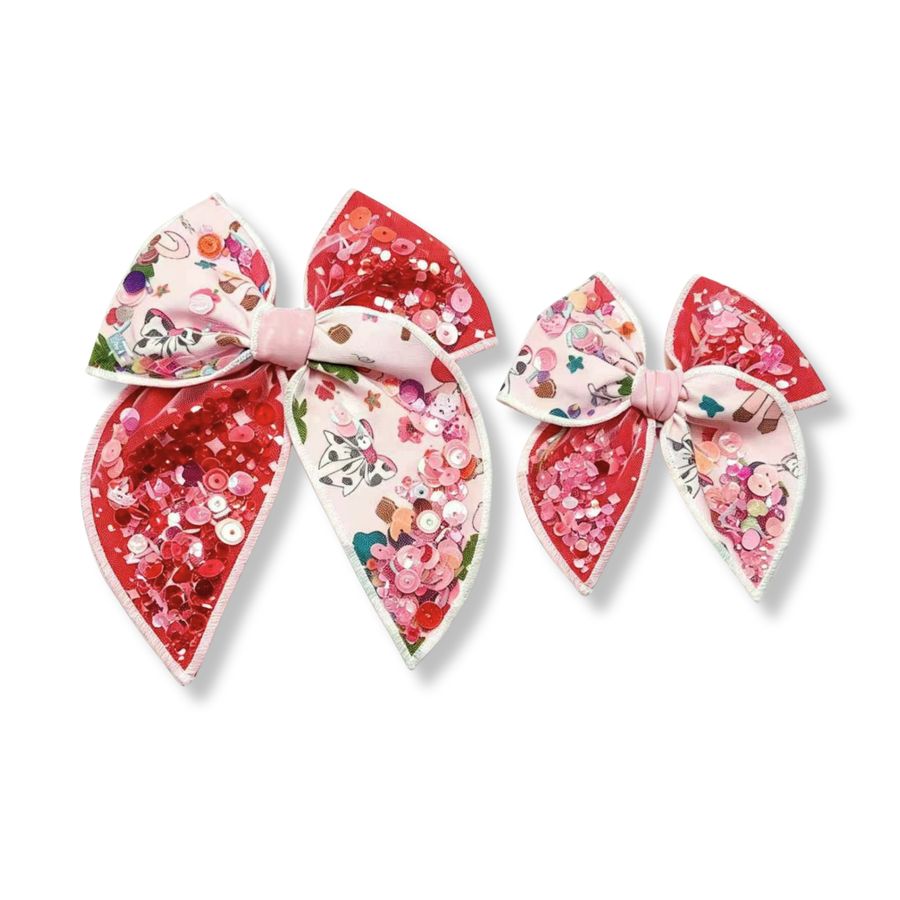 This vibrant shaker bow features alternating panels of bright red shaker ribbon and a whimsical white ribbon printed with colorful storybook-inspired designs, including bows, butterflies, flowers, acorns, and other playful accents. The bow is filled with sparkling red, pink, and iridescent sequins that add eye-catching shine and dimension. 
choose size
Small 4.5" x 4.5"
Large 6.5" x 6.5"