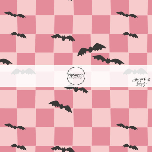Black scattered bats on pink checkered fabric by the yard.