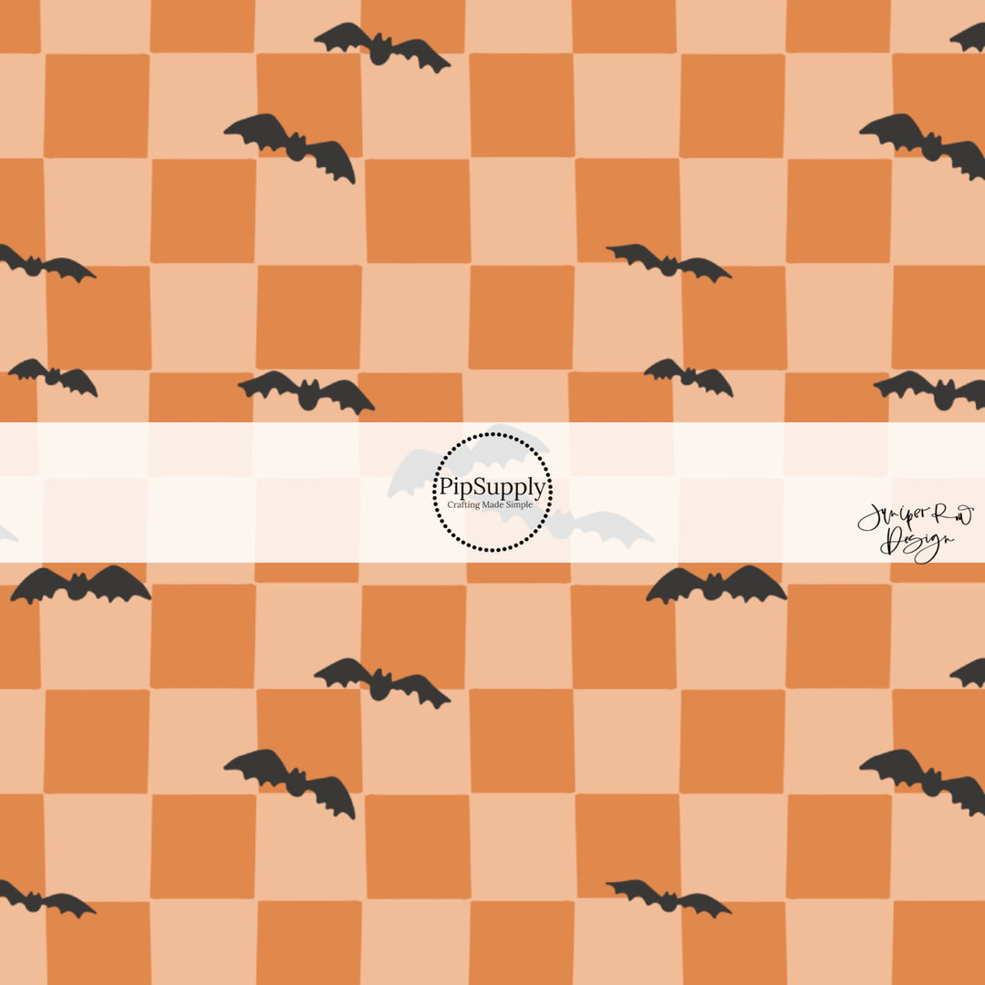 Black scattered bats on orange checkered print fabric by the yard.