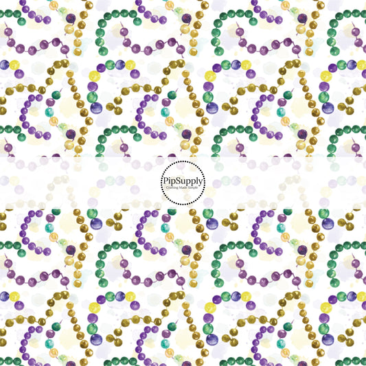 White fabric by the yard with yellow, purple, and green Mardi Gras beads.