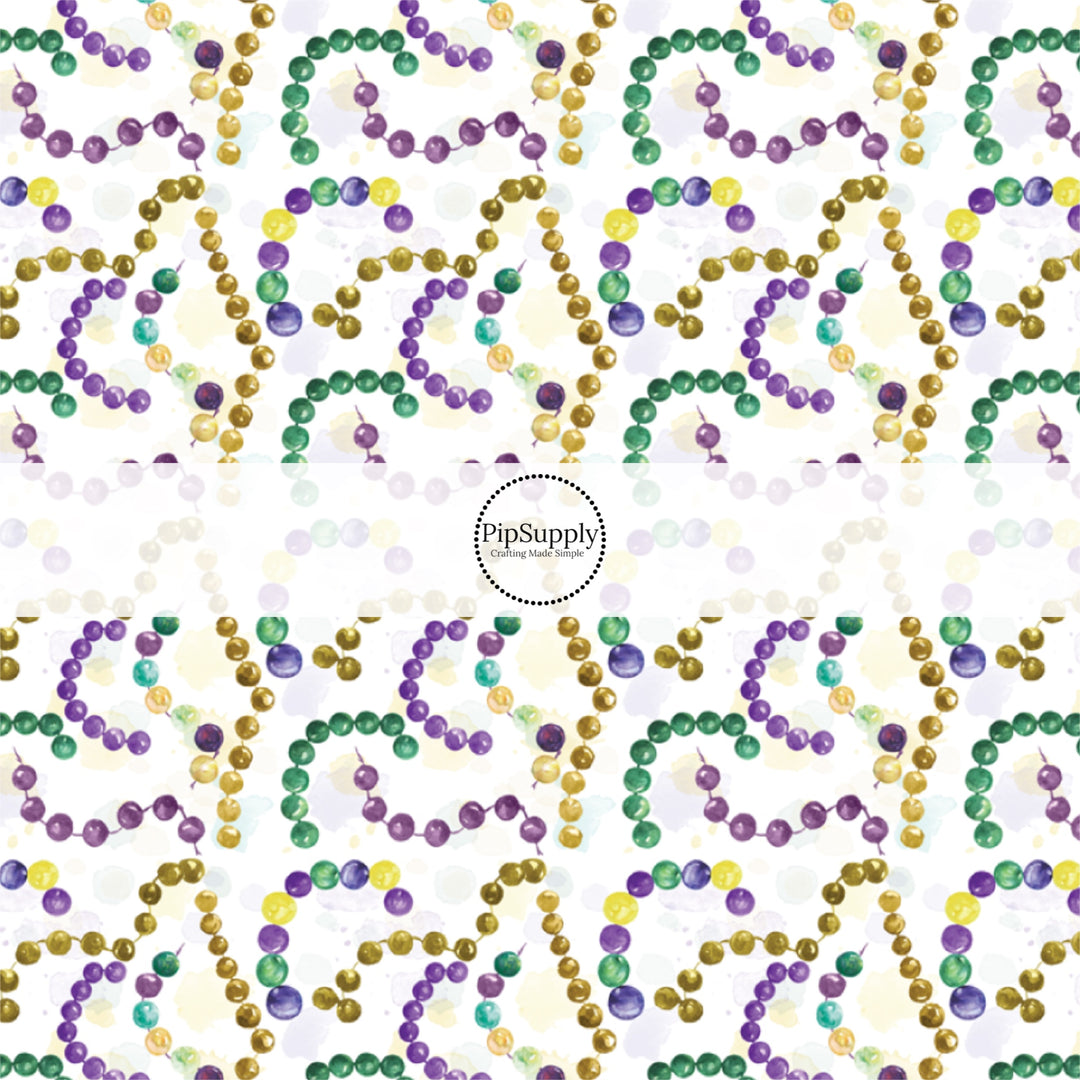 White fabric by the yard with yellow, purple, and green Mardi Gras beads.