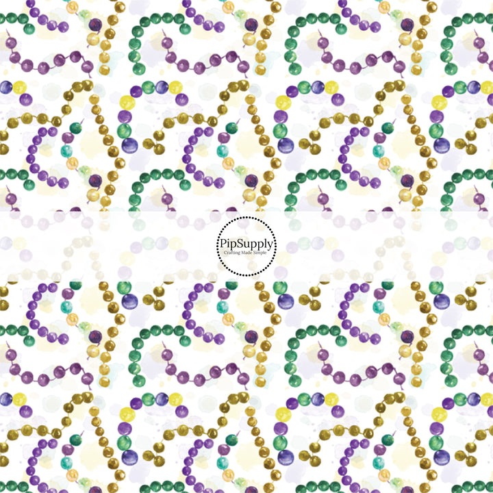 White fabric by the yard with yellow, purple, and green Mardi Gras beads.