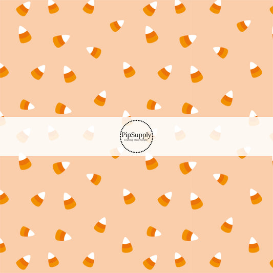 Light orange fabric by the yard with scattered candy corn.