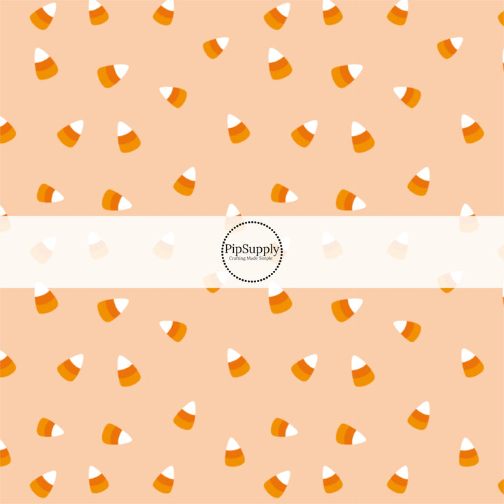 Light orange fabric by the yard with scattered candy corn.