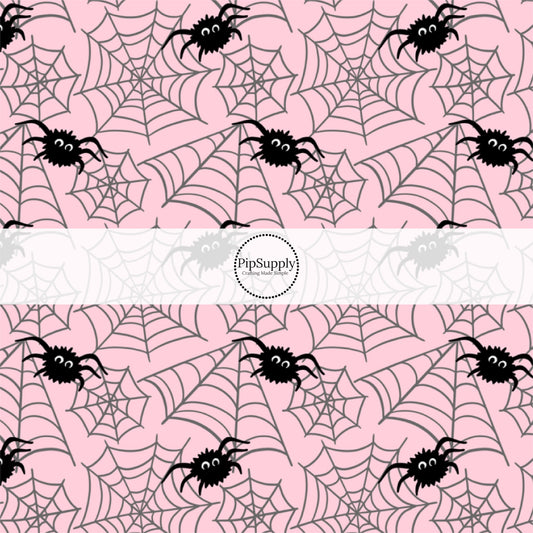 Light pink fabric by the yard with black spiders and spiderwebs.