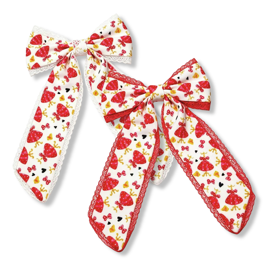 These elegant boutique bows feature a white ribbon printed with red polka-dot dresses, bows, hearts, and coordinating character-inspired accents. One bow is finished with delicate white lace trim, while the other is accented with vibrant red lace trim for a bolder look. The long tails and classic bow silhouette create a timeless design that is both charming and playful.
you chose red or white trim
Large 5.5" X 9.5"