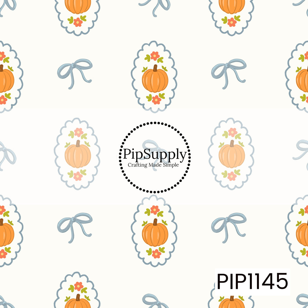 A charming fall pattern featuring orange pumpkins framed by coral flowers and green leaves inside blue scalloped medallions, alternating with delicate blue bows on an ivory background.
