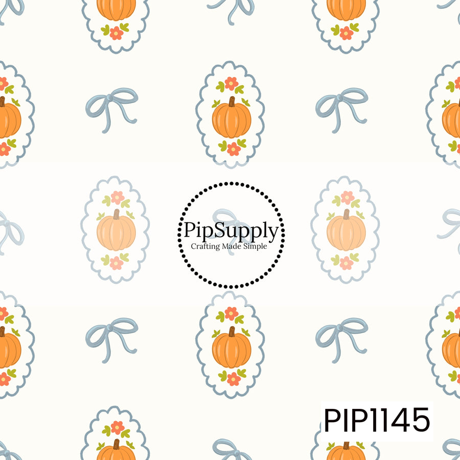 A charming fall pattern featuring orange pumpkins framed by coral flowers and green leaves inside blue scalloped medallions, alternating with delicate blue bows on an ivory background.

