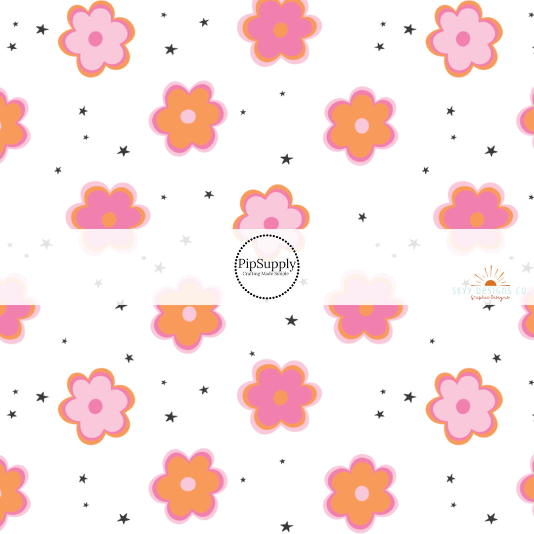 White fabric by the yard with pink and orange daisies and tiny scattered black stars.