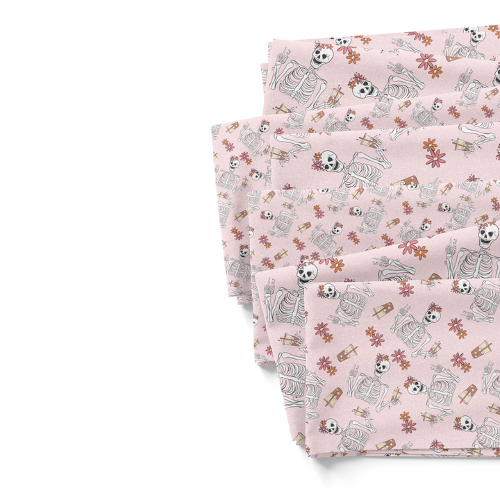 Light pink fabric by the yard fabric swatches with florals and skeletons drinking iced coffee.