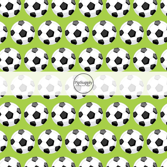Green fabric by the yard with white and black scattered soccer balls.