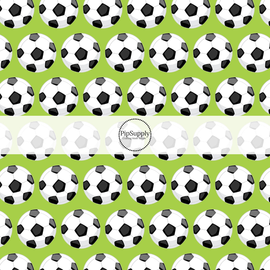 Green fabric by the yard with white and black scattered soccer balls.