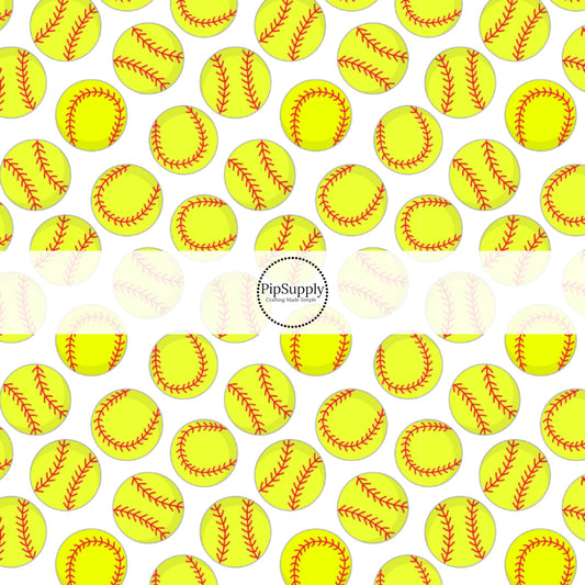 Yellow softballs with red stitching on white fabric by the yard.