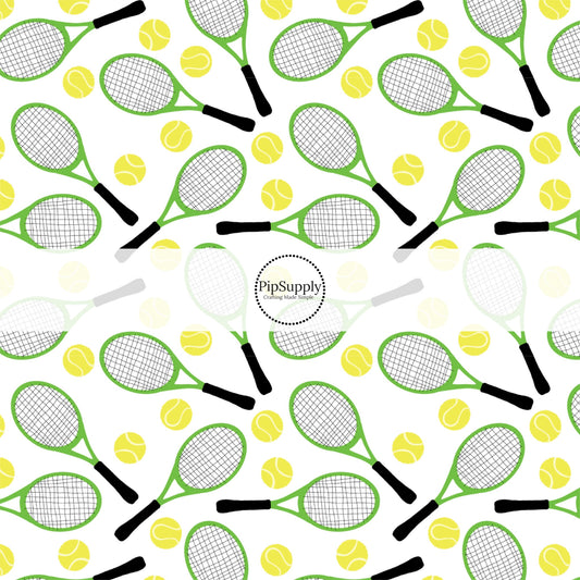 Yellow tennis balls and green tennis rackets on white fabric by the yard.