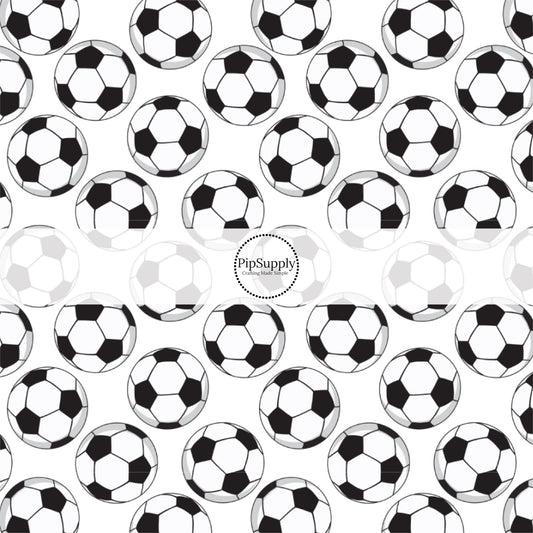Black and white scattered soccer balls on white fabric by the yard.