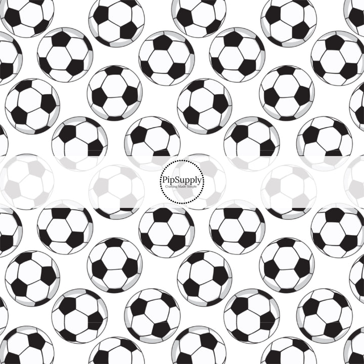 Black and white scattered soccer balls on white fabric by the yard.