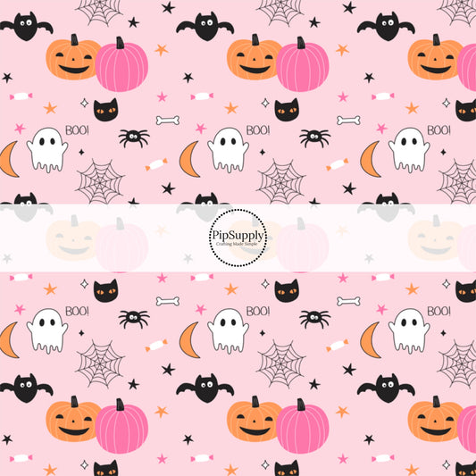 Pumpkins, ghosts, bats, moons, stars, and spider webs on light pink fabric by the yard.