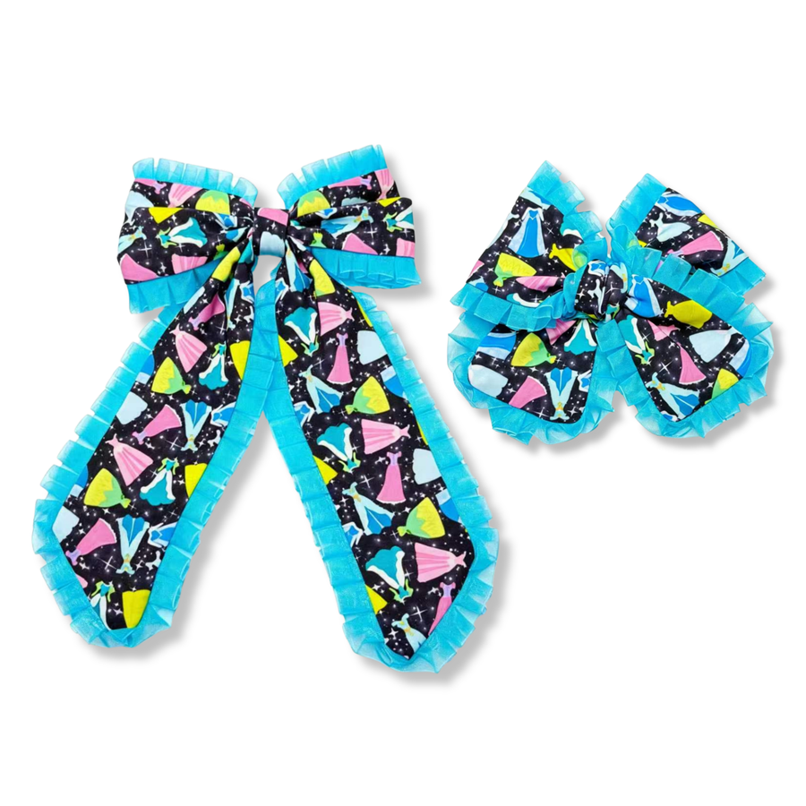Large layered bow made from a black fabric printed with colorful dress silhouettes in shades of blue, pink, yellow, and turquoise, accented with scattered stars. The bow features long flowing tails and is trimmed throughout with bright turquoise ruffled edging. A matching smaller bow with the same print and ruffled trim is shown alongside it. The design is vibrant, playful, and eye-catching with a whimsical, fantasy-inspired aesthetic. available in two sizes
Large 5.5" X 9.5"
Small 5" X 6"