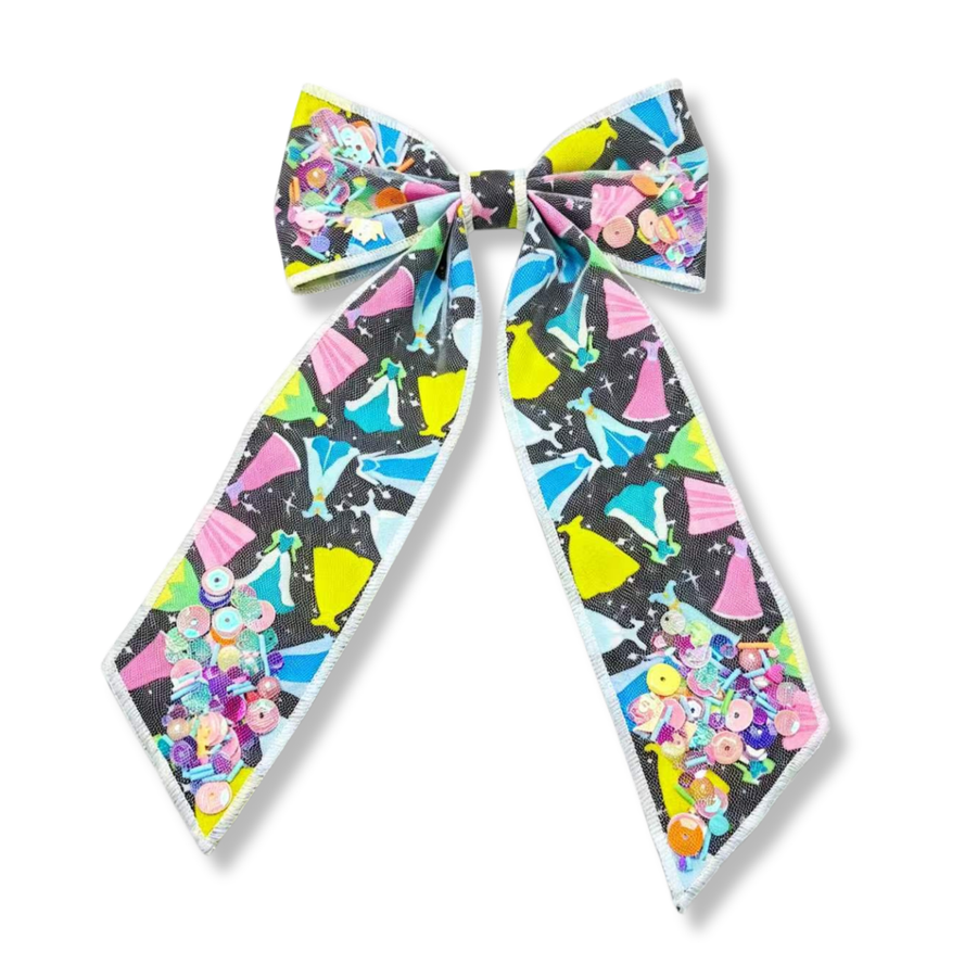 This vibrant shaker bow features a black background printed with colorful princess-inspired gown silhouettes in shades of pink, blue, yellow, and mint. The shaker sections are filled with pastel sequins, beads, and confetti-like embellishments that add sparkle, dimension, and movement. A whimsical accessory perfect for themed outfits, special occasions, or everyday magic.
Bow Sizing 5" x 8.5"