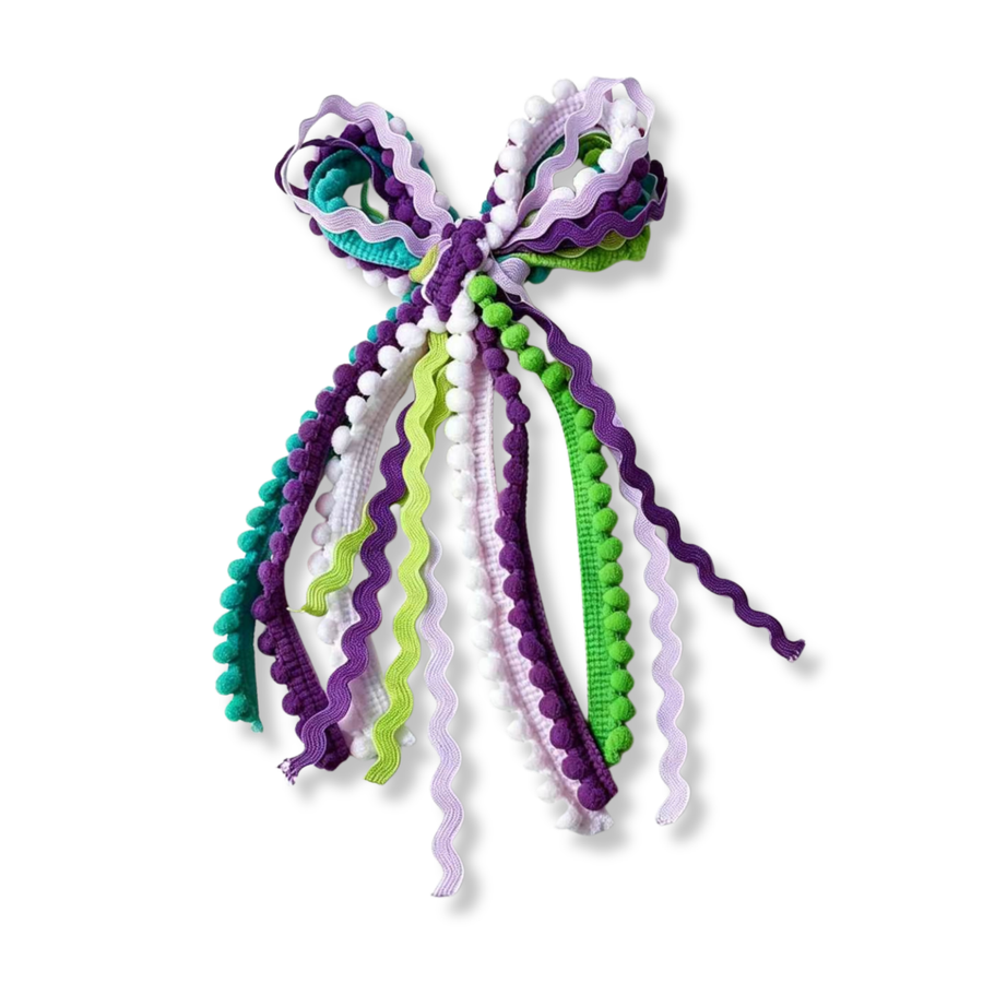 A playful **messy bow** crafted from an assortment of ric rac ribbons, pom-pom trim, and textured woven ribbons in shades of purple, lavender, teal, lime green, and white. The cascading ribbons feature wavy edges, soft pom-pom accents, and varied textures that create beautiful movement, dimension, and a whimsical handcrafted look.

Bow Sizing 5" x 9"