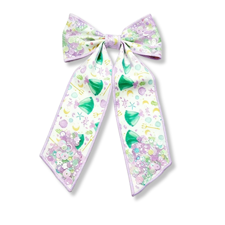 A whimsical shaker bow featuring a dreamy under-the-sea print with seafoam green mermaid inspired  dresses, lavender seashells, starfish, bubbles, and ocean-inspired details on a soft white background. The tails are filled with a sparkling mix of pastel sequins and confetti that add beautiful movement and shimmer.  

Bow Sizing 5" x 8.5"