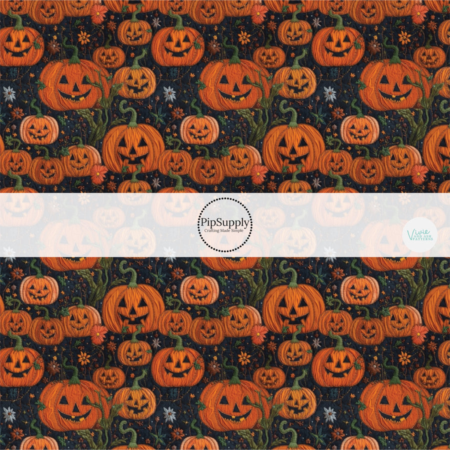 Black fabric by the yard with orange embroidered Jack-o-lantern designs.