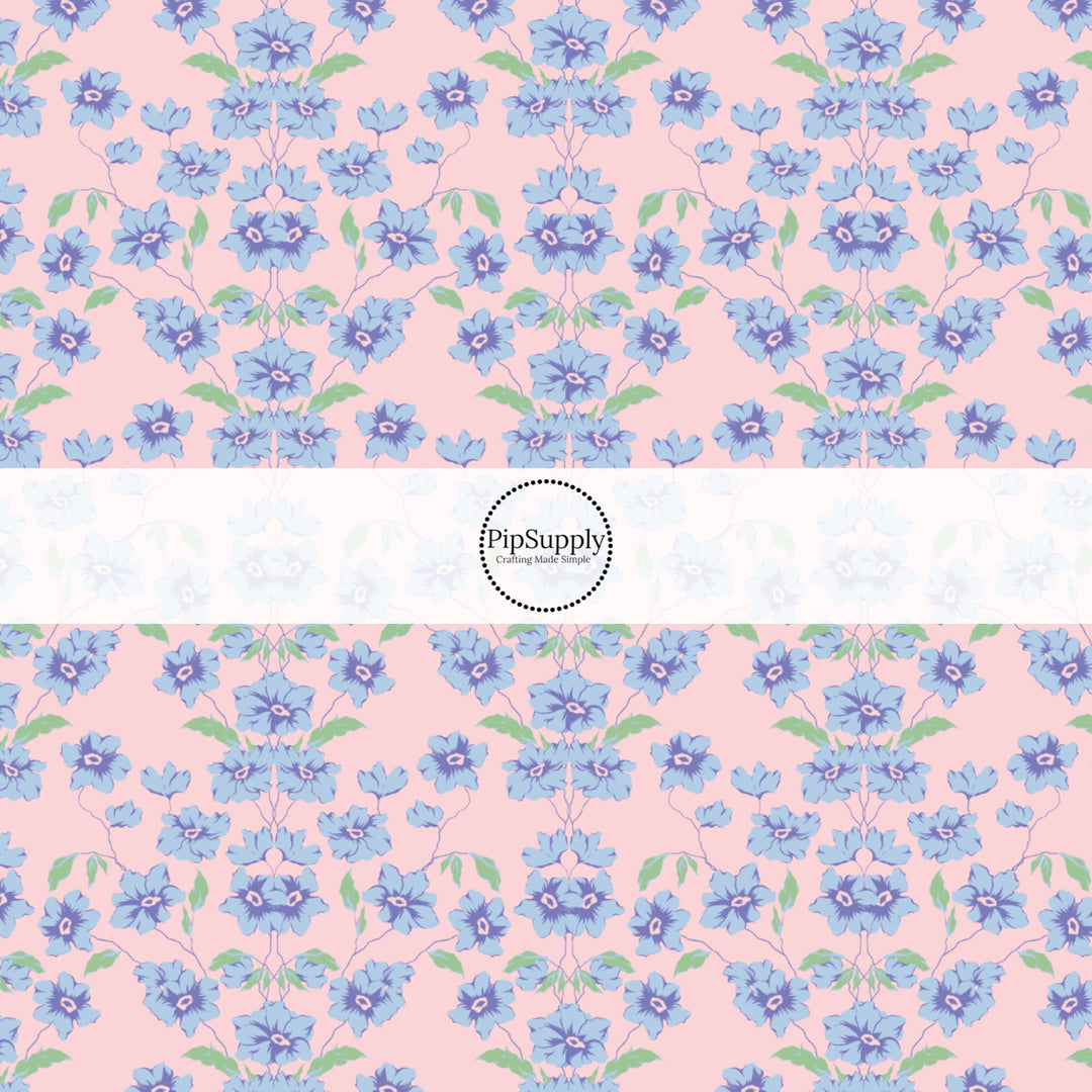 This spring floral themed fabric by the yard features blue flowers on pink. This fun pattern fabric can be used for all your sewing and crafting needs!