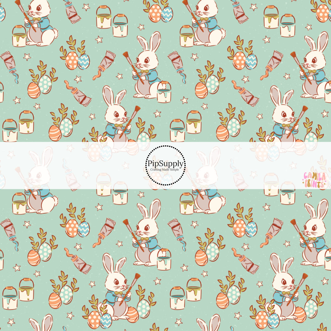 This Easter themed fabric by the yard features Easter bunnies painting Easter eggs on blue. This fun pattern fabric can be used for all your sewing and crafting needs!