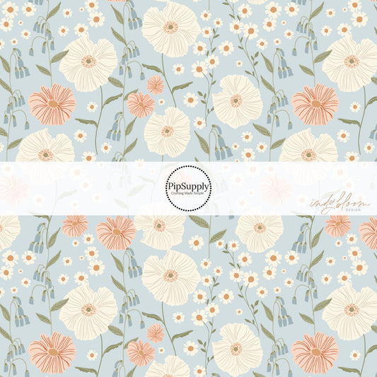 These pastel flowers in a meadow on light blue fabric by the yard features tan, orange, cream, pink, and blush flowers