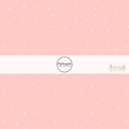 These dot themed pastel pink fabric by the yard features small white dots scattered on light pink. 